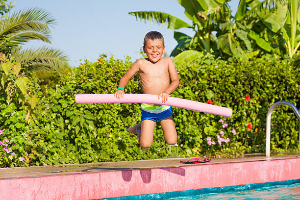 istock Jumping in pool small boy holding inflatable ring 494668896