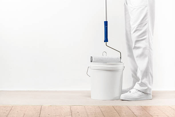Painter man takes the color with paintroller from the bucket