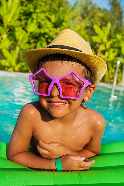 istock Cute boy in star-shaped sunglasses on green airbed 494669742