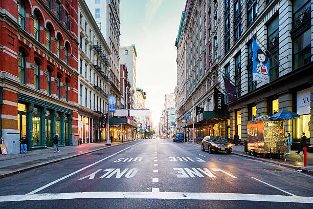 Manhattan Soho Broadway looking North early morning New York City, USA - October 24, 2015: Manhattan Soho Broadway looking North early morning, towards Grace church. The Chrysler building is visible. Several people can be seen using technology, ordering food or walking.  Several store fronts are visible as well as lane markers. soho new york stock pictures, royalty-free photos & images