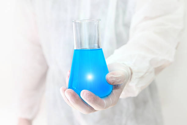 Science research laboratory background, with chemist holding a glass flask with blue liquid with a glowing light. Research and discovery. Glass chemistry equipment. High key tone.