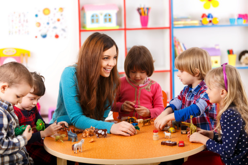 Young woman playing with kids in nursery school