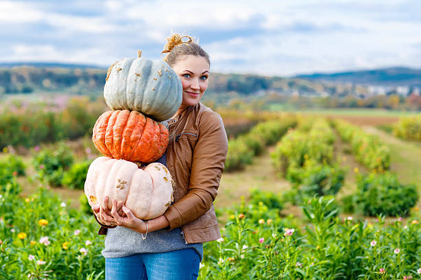 istock Beautiful woman with three huge pumpkins on farm 494698596