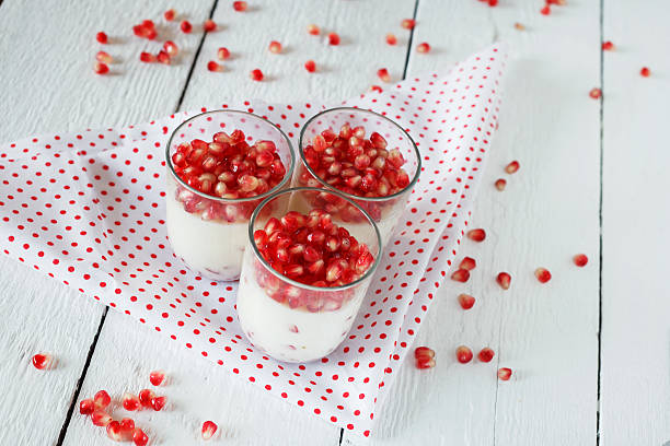 Natural yogurt topped with pomegranate seeds in decorative glass bowl - Healthy natural yoghurt on cloth background