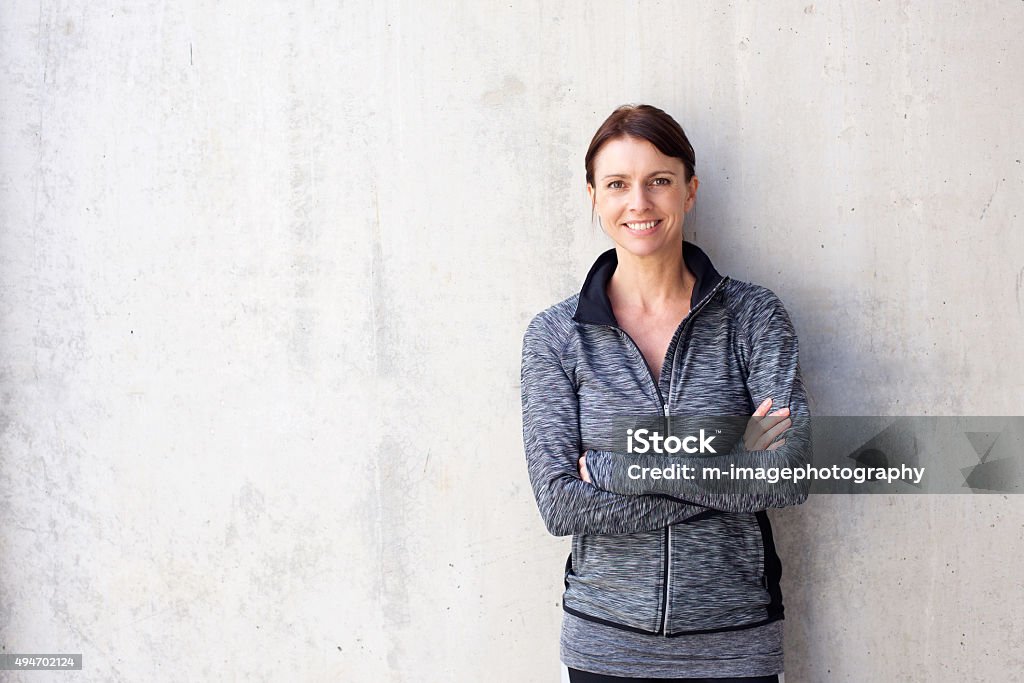 Attractive older sports woman smiling Portrait of an attractive older sports woman smiling against white wall Women Stock Photo