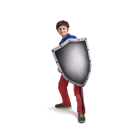 A 10 years old cute boy is holding a shield in front of him like protecting himself from something.