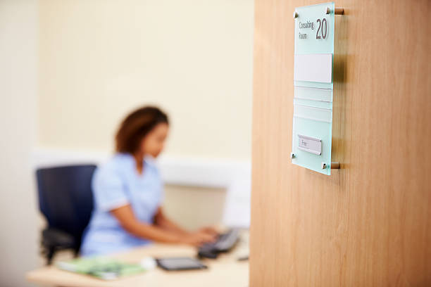 Female Nurse Working At Desk In Office Sitting On Chair
