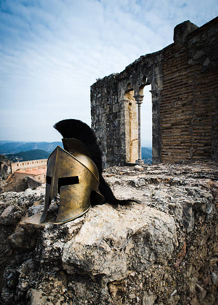 Spartan helmet with black crest on castle ruins.