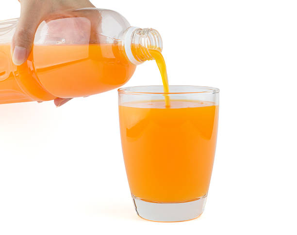 istock Orange juice poured from bottle to a glass 494708825