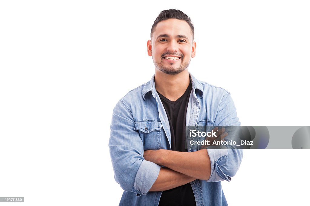 Latin young man in a studio Handsome young Hispanic guy smiling with his arms crossed against a white background Men Stock Photo