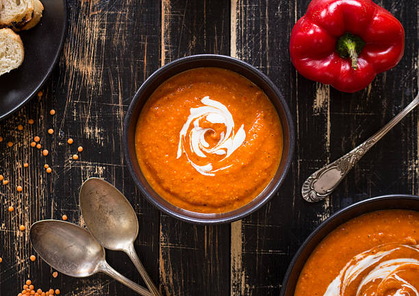 Pumpkin soup with heavy cream Delicious pumpkin soup with heavy cream on dark rustic wooden table with red bell pepper, bread toasts, lentil. Top view red bell pepper stock pictures, royalty-free photos & images