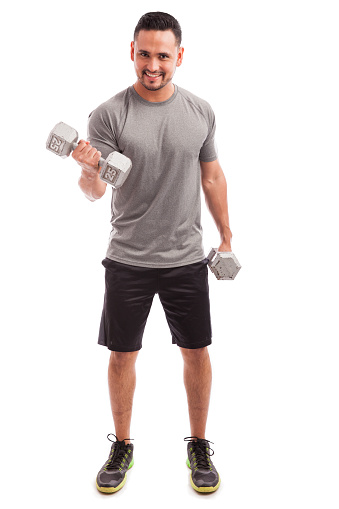 Full length portrait of a young attractive man doing bicep curls with a couple of dumbbells