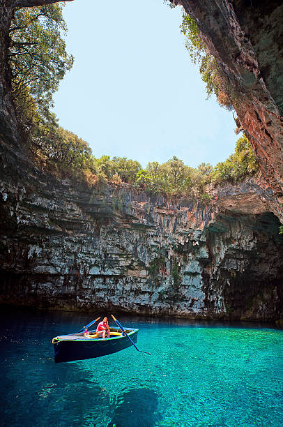 Kefalonia, Greece - June 06, 2015: Worker sits in his boat waiting for tourists to arrive in Melissani Cave, Kefalonia Greece on June 6, 2015.