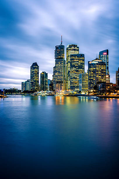 Long exposure shot of Brisbane skyline at dusk. There are some skyscrapers in back and river in front.
