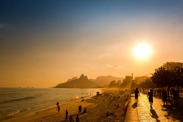 Late afternoon on Ipanema beach in Rio de Janeiro, Brazil Unidentifiable silhouettes enjoy late afternoon sun rays on Ipanema beach in Rio de Janeiro, Brazil.  Ipanema is one of the most expensive places to live in Rio, copacabana rio de janeiro photos stock pictures, royalty-free photos & images