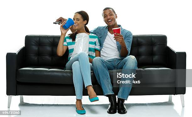 Couple On Couch Eating Food And Watching Tv Stock Photo - Download Image Now - 20-24 Years, 20-29 Years, 2015