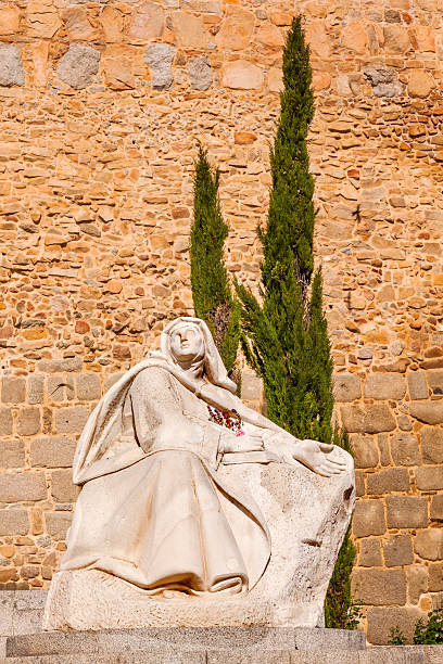 Avila, Spain - May 10, 2014: White Saint Teresa Statue Walls Castle Avila Castile Spain.  Avila described as the most 16th century town in Spain.  Saint Teresa Statue created 1972 by Juan Luis Vassallo. Walls created in 1088 after Christians conquer  Moors