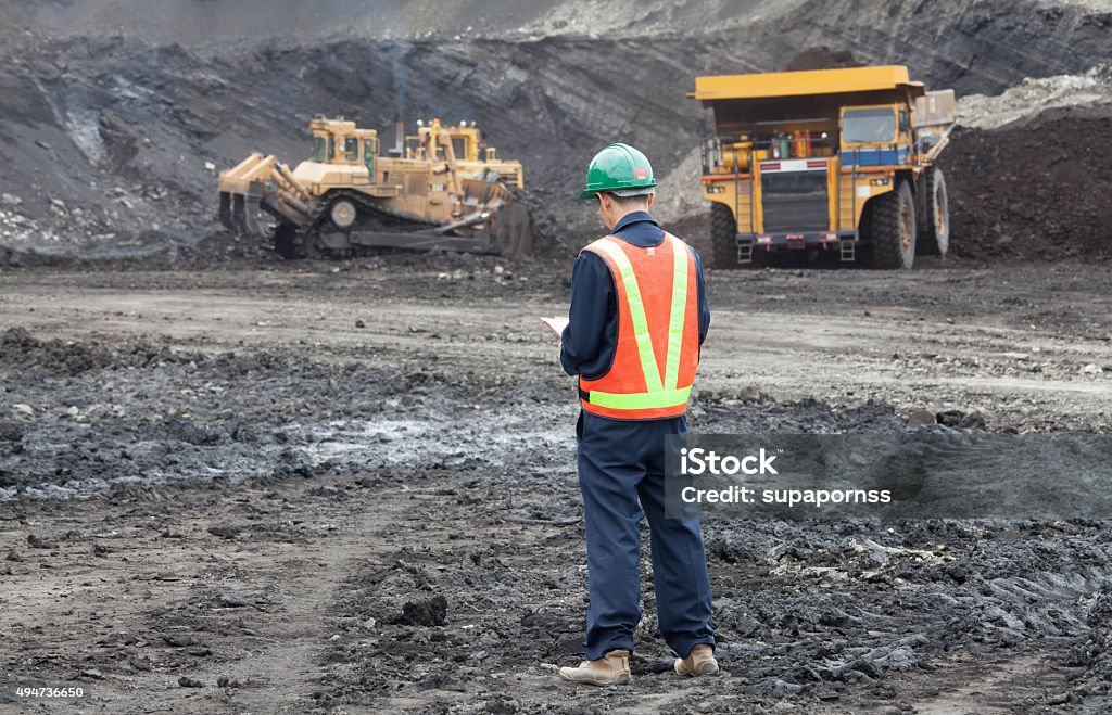 Heavy mining industry worker Coal trucks and loaders are hauling the coal away to to a power plant simultaneously. Mining - Natural Resources Stock Photo