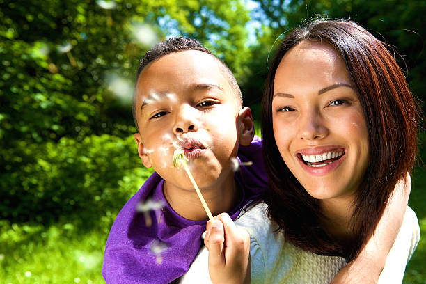 istock Smiling mother with son blowing dandelion 494736797