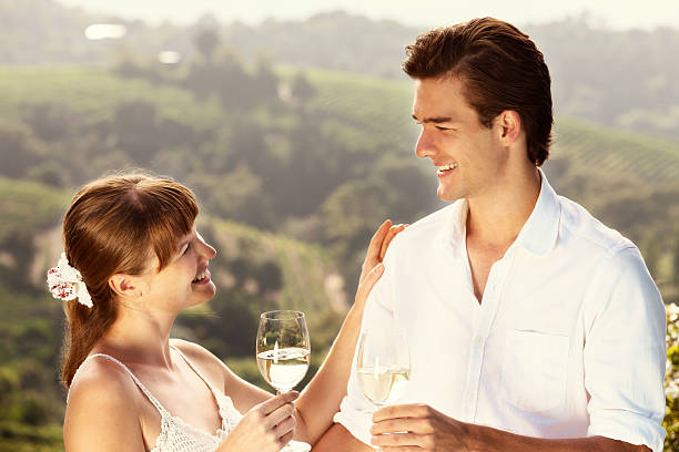 Smiling couple toast each other in idyllic vineyard