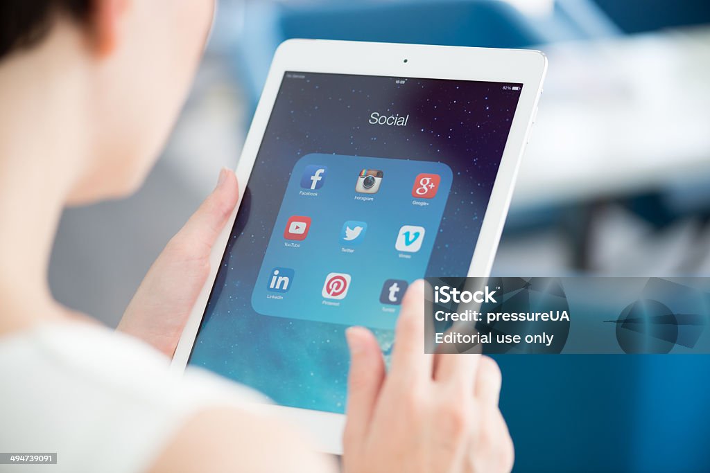 Social media icons on tablet PC screen Kiev, Ukraine - May 21, 2014: Woman looking on social media applications on modern white Apple iPad Air, which is designed and developed by Apple inc. and was released on November 1, 2013. Social Media Stock Photo