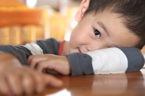 Shallow DOF closeup on an eye of boy in toddler age playing peekaboo over wooden table