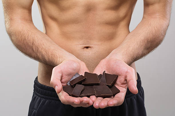 Young fit man holding oscuro trozos de chocolate - foto de stock