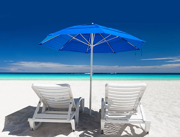 istock Caribbean beach with blue sun umbrellas and white beds 494755508