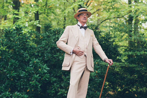 Man posing in stylish summer suit and straw hat outdoors in a garden setting