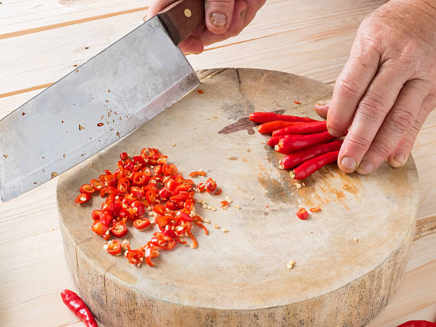 istock Hand chopping chili on chopping block on wood background 494757504