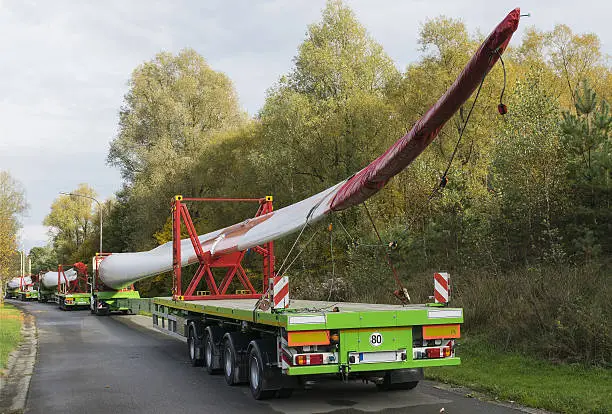 Roadside parking convoy of special trucks with oversize loads transporting rotor blades for wind power plant turbines
