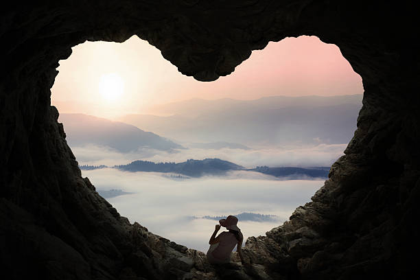 istock Woman sitting inside cave and enjoy mountain view 494762040