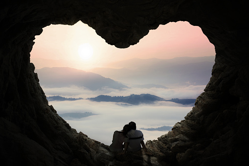 Pareja romántica disfrutar de la vista a las montañas en cave photo