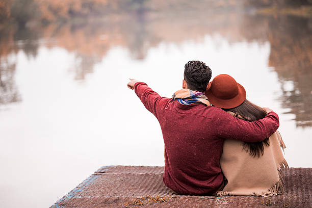 istock Back view of embraced couple relaxing on a pier. 494763864