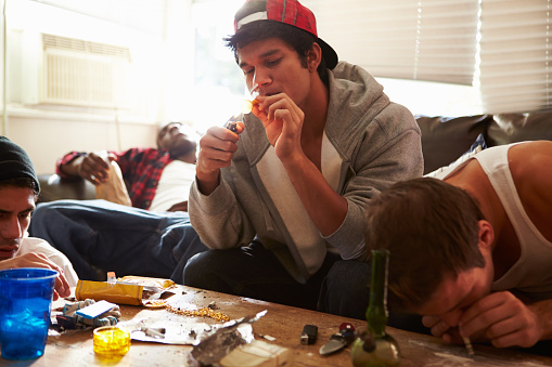Gang Of Young Men Taking Drugs Indoors On Sofa