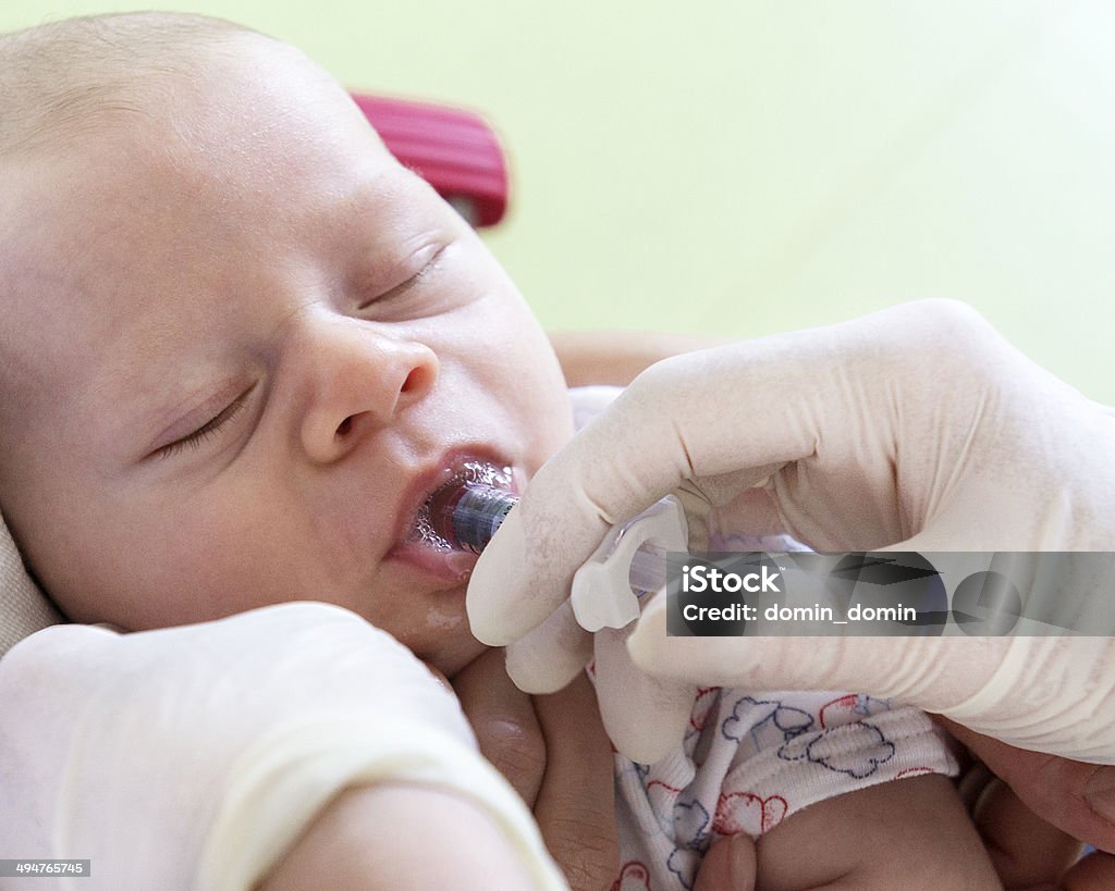 Vaccination, little baby in doctor's clinic, nurse giving vaccine orally Vaccination. Close-up of little baby boy in doctor's clinic, nurse is giving vaccine orally with a syringe. Polio Vaccine Stock Photo