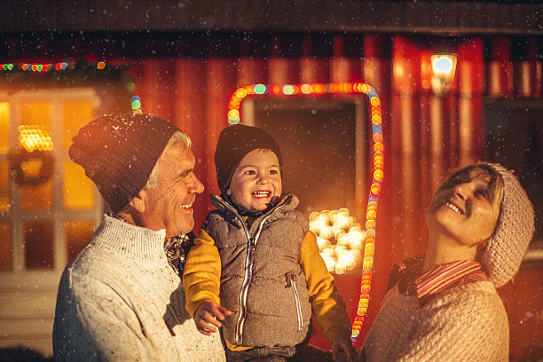 First snow Cute little smiling boy and his grandparents are in the backyard greeting the first snow for the winter season  baby new years eve new years day new year stock pictures, royalty-free photos & images