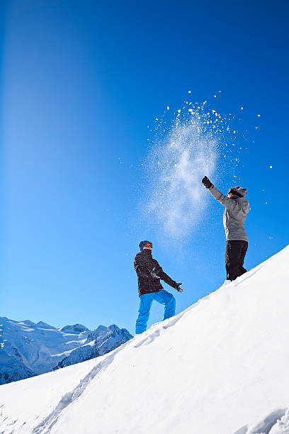 mädchen und jungen spielen im winter skifahrer werfen schnee schneeballschlacht - pair cheerful happiness heterosexual couple stock-fotos und bilder