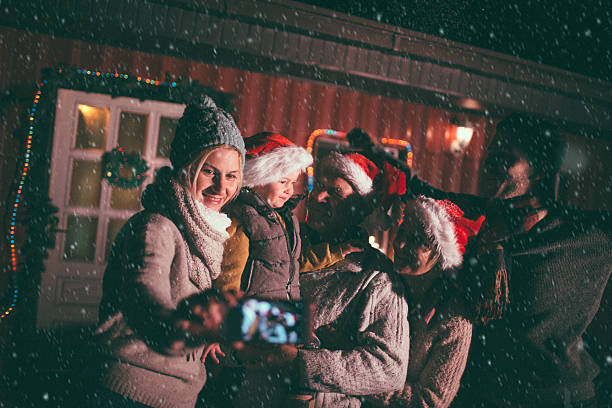 Family portrait on the first snow Cute multi-generation family in the backyard greeting the first snow for the winter season, and capturing the moment on the mobile phone  baby new years eve new years day new year stock pictures, royalty-free photos & images