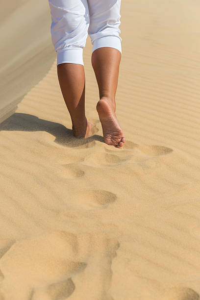 istock Women's beautiful smooth legs on white sand beach 494780021