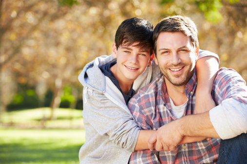 Portrait Of Father And Son In Countryside Smiling To Camera