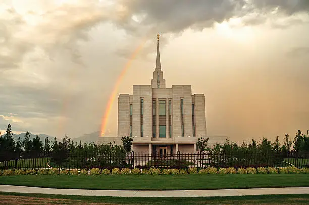 The West side of the Oquirrh Mountain Temple of the Church of Jesus Christ of Latter-day Saints ("LDS" or aka Mormon), located in South Jordan, Utah. A double rainbow shines on the North side. A sculpture of the Angel Moroni sits atop the spire. The temple is centered; landscape orientation. This temple has been in operation since 2009. Mormons go to any of these temples to be married for life and eternity. 