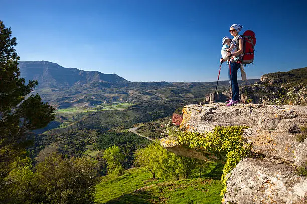 Photo of Hiker with baby relaxing on cliff and enjoying valley view