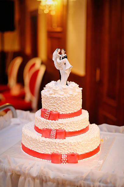 istock three-tiered white wedding cake with red ribbons 494780897