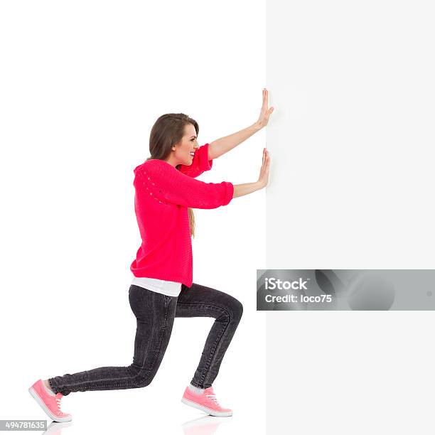 Young Woman Pushing The Wall Stock Photo - Download Image Now - Pushing, Women, Surrounding Wall