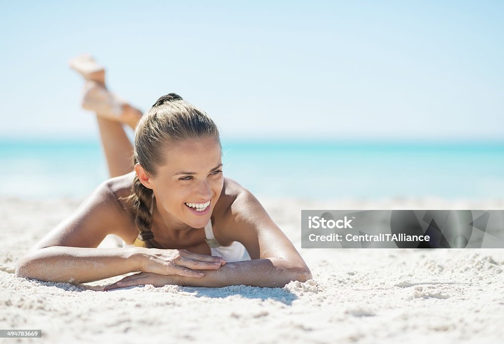 Portrait of smiling young woman laying on beach Portrait of smiling young woman laying on beach and looking on copy space Beach Stock Photo