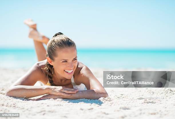 Portrait Of Smiling Young Woman Laying On Beach Stock Photo - Download Image Now - Beach, Sunbathing, Women