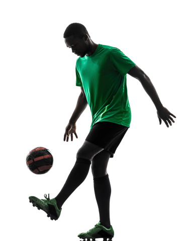 one african man soccer player green jersey juggling in silhouette on white background