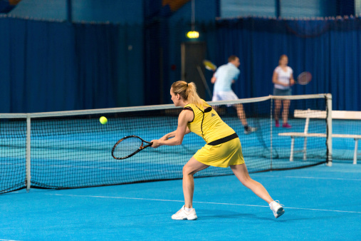 Female indoor tennis player in action.   