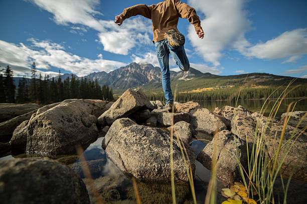 istock Man jumps rock to rock in mountain lake 494786708